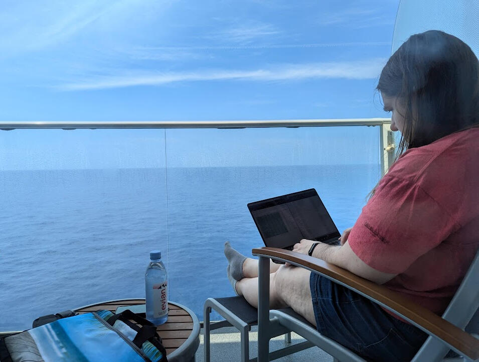 Writing by the Ocean A writer's laptop screen with a sun setting on open ocean behind it.